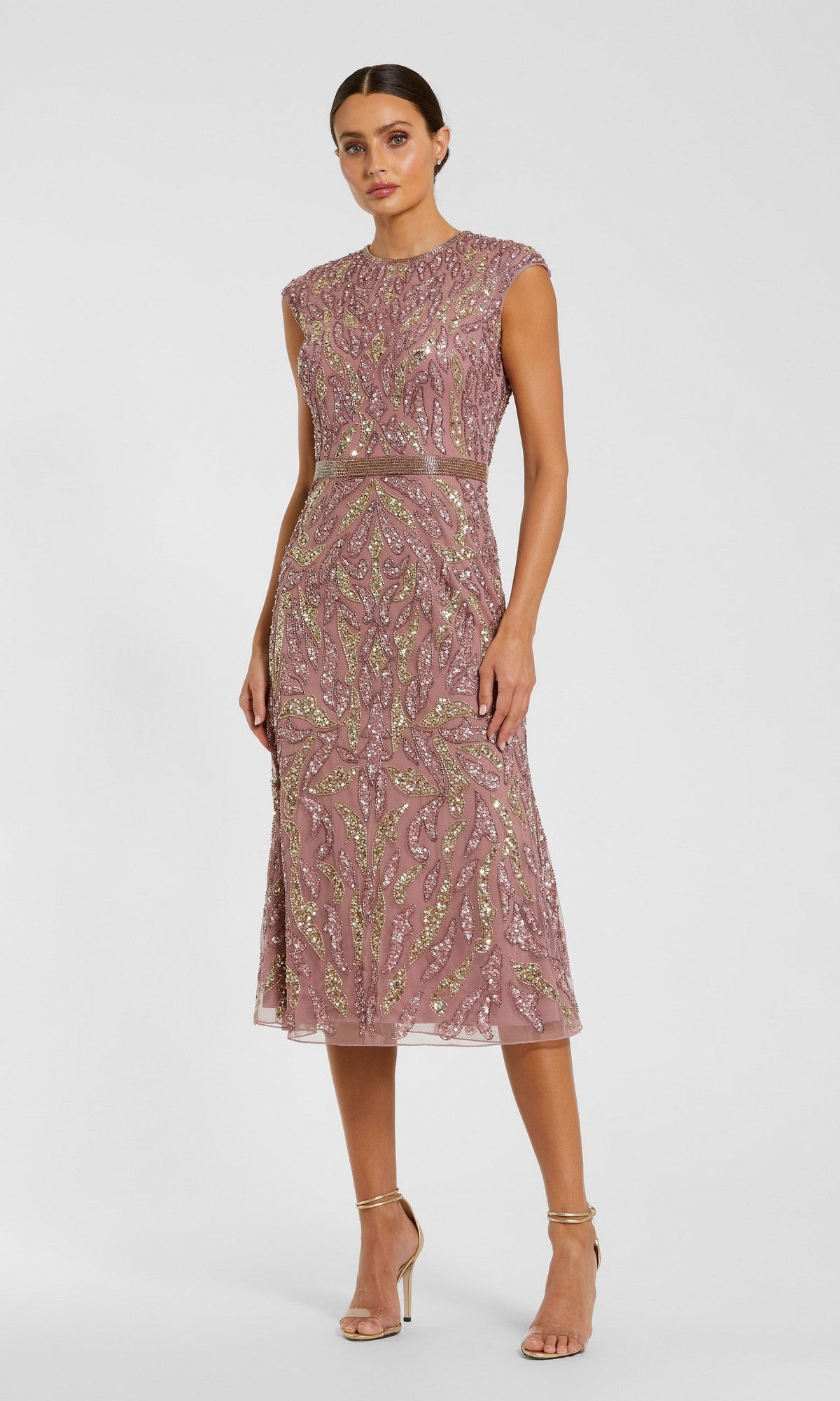 A woman in a sleeveless, knee-length vintage lilac beaded sheath dress with intricate patterns, standing against a plain light gray background and wearing strappy high heels. This elegant look is the perfect modest midi party dress, showcasing the timeless glamour of the Modest Midi Party Dress: Mac Duggal 23049 in Vintage Lilac.